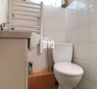 Badezimmer in einem Einfamilienhaus mit weißen Fliesen, Waschbecken und WC.