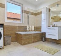 Ein Badezimmer in einem Einfamilienhaus mit Badewanne, Dusche und Waschmaschine, Boden mit Holzdekor.