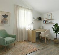 Ein Arbeitszimmer in einem Einfamilienhaus mit einem Sessel, einem Tisch und einem Boden in Holzoptik.
