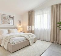Helles Schlafzimmer mit großem Bett, Vorhängen und Pflanzen in einem Einfamilienhaus.