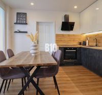 Küche in einer 3-Zimmer-Wohnung mit Holzdekor, Tisch und bunten Stühlen.