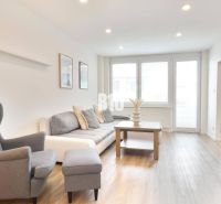 Wohnzimmer mit Sofa, Sessel und Holzboden in einer 3-Zimmer-Wohnung.