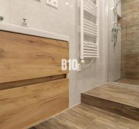 Badezimmer in einer 3-Zimmer-Wohnung mit Boden und Fliesen in Holzoptik.