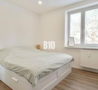 Schlafzimmer in einer 3-Zimmer-Wohnung mit Bett, Schreibtisch und Boden in Holzoptik.