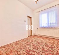 Ein Zimmer in einem Einfamilienhaus mit Teppichboden, Heizkörper und Vorhang am Fenster.