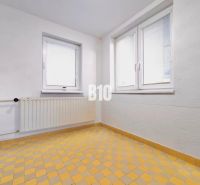 Weiße Wand, Fenster, Heizkörper und gelber Fliesenboden in einem Einfamilienhaus.