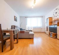 Wohnzimmer mit Holzboden in einer Zweizimmerwohnung mit Sofa und Essecke.