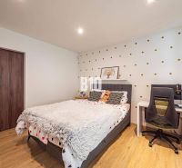 Schlafzimmer in einem Einfamilienhaus mit gepunkteter Tapete, Bett, Tisch und Boden mit Holzdekor.