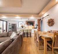 Offener Raum in einem Einfamilienhaus mit Sofa, Küche und Esstisch, Boden mit Holzdekor.