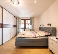 Schlafzimmer mit Holzboden, Kleiderschrank und gepolstertem Bett in einem Einfamilienhaus.