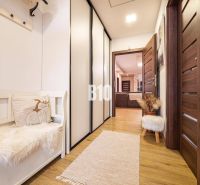 Flur in einem Einfamilienhaus mit einem Boden in Holzoptik, Bank und Schränke.