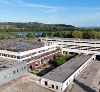 Produktionsräume in Levice mit verlassenen Gebäuden, umgeben von Natur und einer Wasserfläche.
