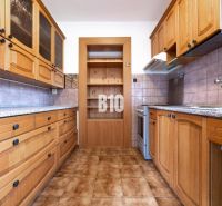 Küche in einem Einfamilienhaus mit Holzschränken und Fliesenboden.