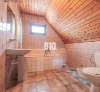 Ein Badezimmer in einem Einfamilienhaus mit Keramikfliesen und einer Holzdecke.