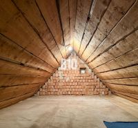 Podkrovný priestor s drevenými stenami a tehlovou stenou v rodinnom dome.

Dachboden mit Holzwänden und einer Ziegelwand in einem Einfamilienhaus.
