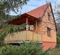 Ein Einfamilienhaus in Vlkas, umgeben von Grün, traditionell mit einem schrägen Dach, einem Holzbalkon.