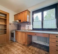 Küche in einem Einfamilienhaus mit Holzschränken und großem Fenster, Boden mit Holzdekor.