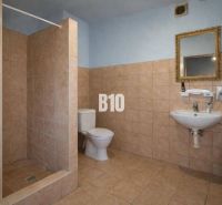 Badezimmer in Produktionsräumen mit Toilette, Waschbecken und Duschkabine.