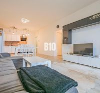 Wohnzimmer mit Küche, weiße Möbel, Sofa und Boden mit Holzdekor.