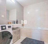 Badezimmer mit Badewanne, Waschbecken und Waschmaschine in einer 3-Zimmer-Wohnung.