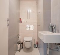 Badezimmer in einer 3-Zimmer-Wohnung mit einfachen hellen Fliesen und sanitären Einrichtungen.