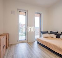 Ein Zimmer in einer 3-Zimmer-Wohnung mit einem Sofa, Schränken und einem Boden in Holzoptik.