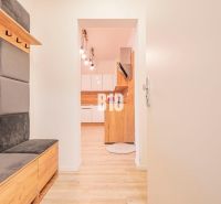 Eingangsflur mit Sitzgelegenheit und Blick in die Küche, 3-Zimmer-Wohnung mit Holzdekorboden.