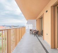 Balkon einer 3-Zimmer-Wohnung in Nitra mit Blick auf die Stadt und einer Sitzgelegenheit im Freien.