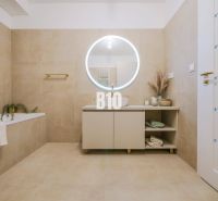 Badezimmer mit rundem Spiegel und beigen Fliesen in einer 2-Zimmer-Wohnung.