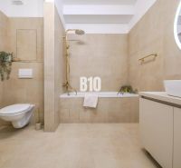 Badezimmer in einer 2-Zimmer-Wohnung mit beigen Fliesen, eingebauter Badewanne und hängender Toilette.