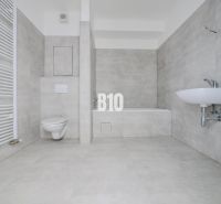 Badezimmer mit Badewanne, Waschbecken und Toilette in einer neuen 2-Zimmer-Wohnung.