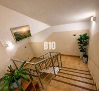 Innenraum eines Gebäudes mit Blumen, Treppe und einem Naturbild an der Wand.