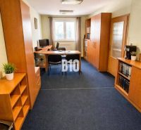Büro mit blauem Teppichboden und Holzmöbeln im Gebäude.