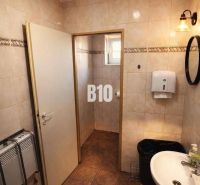 Badezimmer mit Waschbecken, weißem Seifenspender und Boden mit braunem Dekor im Gebäude.