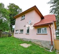 Einfamilienhaus in Makov mit rosa Fassade, Garten und Satellitenschüssel an der Wand.