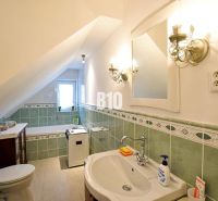 Ein Badezimmer in einem Einfamilienhaus mit grünen Fliesen und einer Dachschräge.