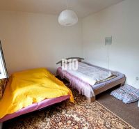 Ein Zimmer in der Hütte mit zwei Betten, einem offenen Fenster und einem gemusterten Teppich.