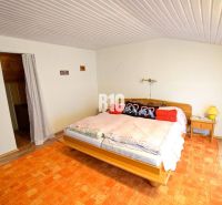 Schlafzimmer in einer Hütte mit Bett, Vorhängen und orangem Teppich.