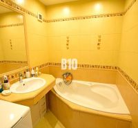 Badezimmer mit gelben Fliesen, Badewanne, Waschbecken und Spiegel in einer 3-Zimmer-Wohnung.