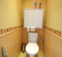 Toilette mit beigen Fliesen und einem Wandschrank in einer 3-Zimmer-Wohnung.