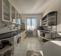 Küche in einer 2-Zimmer-Wohnung mit weißen Schränken und schwarzer Arbeitsplatte.