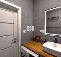 Badezimmer mit Waschbecken, Spiegel und Boden mit Holzdekor in einer 3-Zimmer-Wohnung.