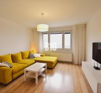 Wohnzimmer in einer 3-Zimmer-Wohnung mit einem markanten gelben Sofa und einem Boden in Holzoptik.