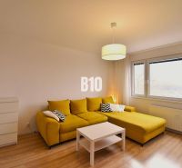 Wohnzimmer einer 3-Zimmer-Wohnung mit gelbem Sofa und Boden in Holzoptik.