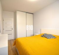 Schlafzimmer in einer 3-Zimmer-Wohnung mit Holzboden und gelber Bettdecke.