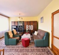 Wohnzimmer in einem Einfamilienhaus mit Sofas, Sesseln, Vitrine und Teppich.