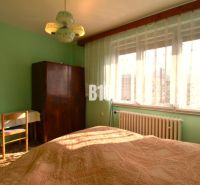 Schlafzimmer im Einfamilienhaus mit Fenster, Vorhängen, Schrank und Tisch.