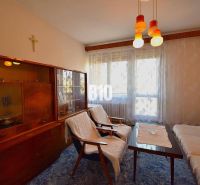 Wohnzimmer in einem Einfamilienhaus mit Retro-Möbeln und Vorhängen am Fenster.
