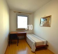 Einfaches Zimmer mit Tisch, Bett und Boden in Holzoptik in einer Wohnung mit mehr als 5 Zimmern.