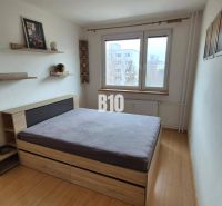 Einfaches Schlafzimmer mit Bett und Holzregalen in einer Wohnung mit 5 oder mehr Zimmern.